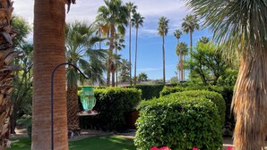 A well-maintained garden with palm trees, a green lawn, and pink flowers. - STUNNING LUXURY ESTATE IN THE EXCLUSIVE MESA AREA OF PALM SPRINGS (Palm Springs)