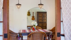 A dining area with a table set for two, surrounded by wicker chairs, a vase with flowers, and a guitar on the wall. - STUNNING LUXURY ESTATE IN THE EXCLUSIVE MESA AREA OF PALM SPRINGS (Palm Springs)