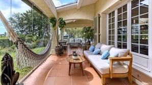 Une terrasse ensoleillée avec un hamac, un canapé et une table.