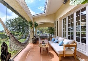 Eine sonnendurchflutete Terrasse mit einer Hängematte, einer Couch und einem Tisch.