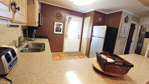 A kitchen with granite countertops, a toaster, a refrigerator, and a wicker basket on the counter.