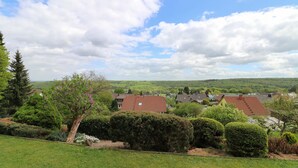A residential area with houses, green hills, and a clear sky. - Large, bright apartment right next to the forest with a beautiful view (Welschneudorf)