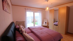 A bedroom with a bed, a chair, a wardrobe, and a radiator. - Large, bright apartment right next to the forest with a beautiful view (Welschneudorf)