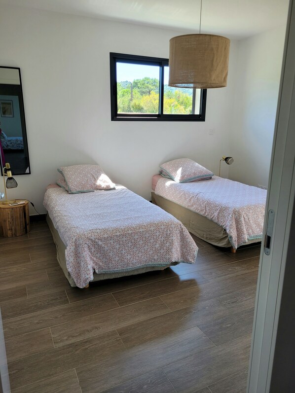 Un dormitorio con dos camas, una ventana y una lámpara colgante.