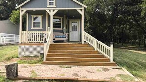 A two-story house with a front porch, a staircase leading to the entrance, and a small front yard.