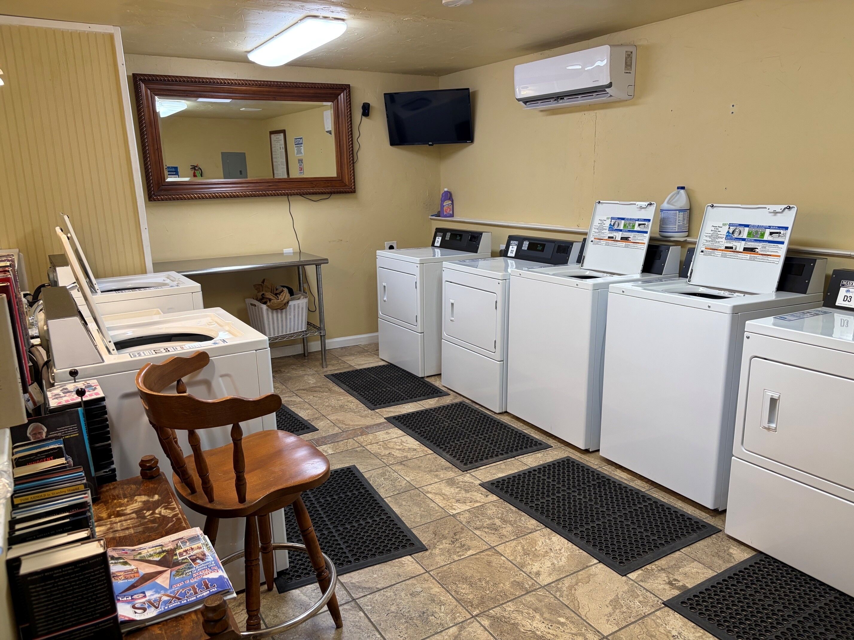 A laundry room with a washing machine, dryer, and a chair.
