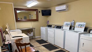A laundry room with a washing machine, dryer, and a chair.