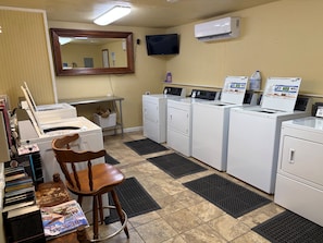 A laundry room with a washing machine, dryer, and a chair. - Lakefront Escape on 14+ Private Acres | Fish, Swim & Relax (Little Elm)