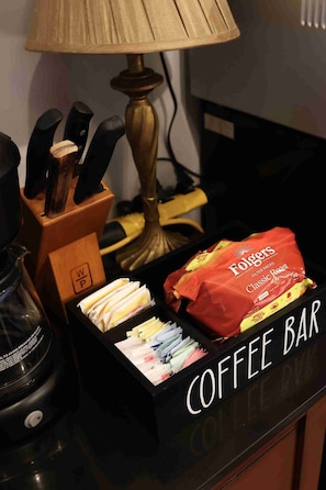 A coffee bar with a coffee maker, a lamp, and a bag of Folgers Classic Roast coffee.
