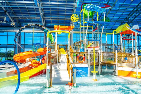 An indoor water park with slides, water features, and play structures.