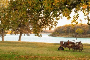 Ein Traktor in der Nähe eines Gewässers, umgeben von Bäumen und Gras.