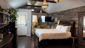 A bedroom with a bed, a TV, a wooden ceiling, and a plant.