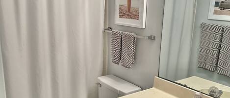 A bathroom with a toilet, sink, and shower curtain.