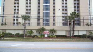 A multi-story hotel with a central glass elevator shaft, balconies, and a sign for 'Shades Retreat'.