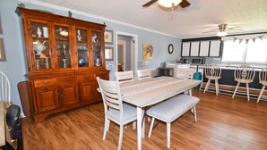 A dining area with a wooden table and chairs, a white bench, and a wooden cabinet with glass doors.