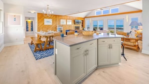A spacious kitchen with a large island, wooden accents, and a view of the ocean.