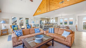 A spacious living room with a sectional sofa, a coffee table, and a view of the kitchen and dining area.