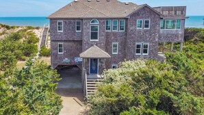 A two-story house with a covered entryway and a view of the ocean.
