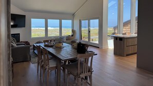 Un interior moderno con comedor, ventanas amplias y vista al océano.