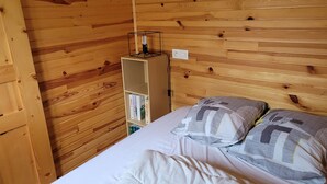 Una habitación con paneles de madera, una cama, almohadas y una estantería.