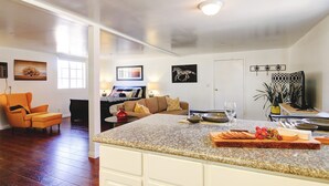 A spacious living area with a kitchen island, wooden flooring, and a cozy seating arrangement. - Wine Country Ranch Escape - Unplug, live by horses on a real ranch, close to wineries! (Buellton)