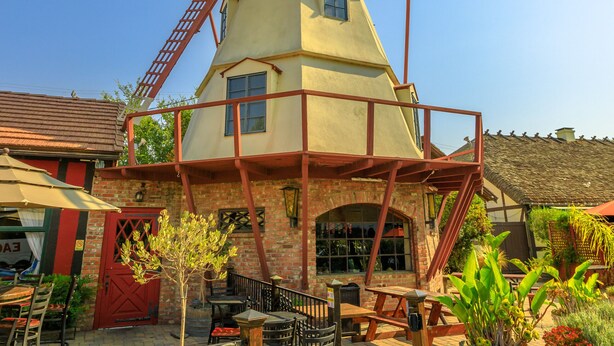 A windmill with a red lattice structure, surrounded by outdoor seating and potted plants. - Wine Country Ranch Escape - Unplug, live by horses on a real ranch, close to wineries! (Buellton)