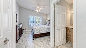 Quarto com cama, penteadeira, cômoda e ventoinha no teto.