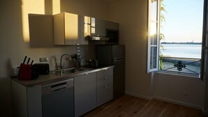 A modern kitchen with a dishwasher, a sink, and a stove. There is a window with a view of the water.