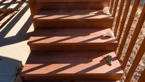 A wooden staircase with a railing, leading up to a building.