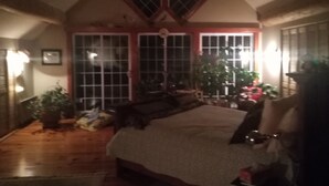 A bedroom with a large bed, two windows, and a wooden ceiling.