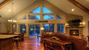 A spacious living room with a fireplace, wooden furniture, and large windows. - Shiprock Cabin -  Modern 3 Bedroom 3.5 bathroom cabin with fire table (Nemo)