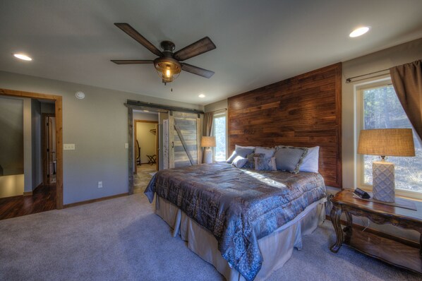 A bedroom with a large bed, a ceiling fan, and a window with curtains. - Shiprock Cabin - Modern 3 Bedroom 3.5 bathroom cabin with fire table (Nemo)