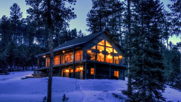 A log cabin with a large deck and multiple windows, surrounded by snow and trees. - Shiprock Cabin -  Modern 3 Bedroom 3.5 bathroom cabin with fire table (Nemo)