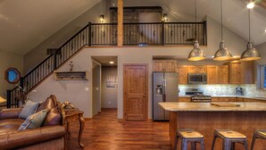 A spacious kitchen with a wooden island, stainless steel appliances, and a mezzanine with a staircase. - Shiprock Cabin -  Modern 3 Bedroom 3.5 bathroom cabin with fire table (Nemo)