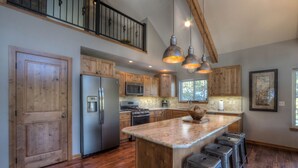 A spacious kitchen with wooden cabinets, a large island with bar stools, stainless steel appliances, and pendant lighting. - Shiprock Cabin -  Modern 3 Bedroom 3.5 bathroom cabin with fire table (Nemo)