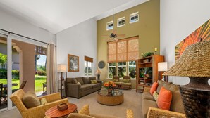 A spacious living room with wicker furniture, a round coffee table, and a large decorative pot.
