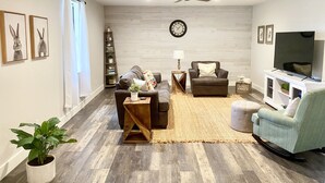 A modern living room with a sofa, armchair, coffee table, and television. - Bright, Spacious, Family-Friendly, 8 Blocks to Main St (Fredericksburg)