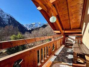 A wooden balcony with a view of snow-capped mountains.