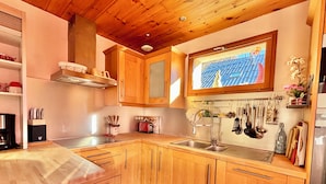 A modern kitchen with wooden cabinets, a stainless steel sink, and a window with a cityscape view. - CHALET "Les roses de Jean" 2 to 10 people (VENOSC)