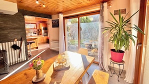 A cozy interior with a wooden ceiling, a dining area with a table set for two, and a kitchen in the background. - CHALET "Les roses de Jean" 2 to 10 people (VENOSC)