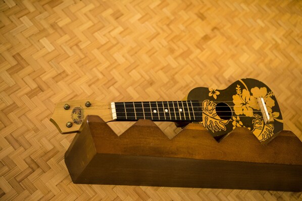 A guitar on a wooden stand with a woven floor.