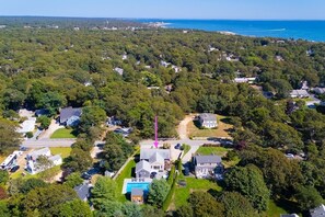 An aerial view of a residential area with houses, a swimming pool, and a road. - Point Pleasant: 082-H Heated Pool, Walk to Beach, Close to everything in Harwich! (West Harwich)