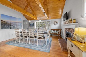 A dining area with a wooden ceiling, a fireplace, and a large window. - Point Pleasant: 082-H Heated Pool, Walk to Beach, Close to everything in Harwich! (West Harwich)