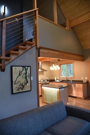 A modern interior with a staircase, a kitchen area, and a seating area. - Romantic island retreat surrounded by majestic trees (Shelton)