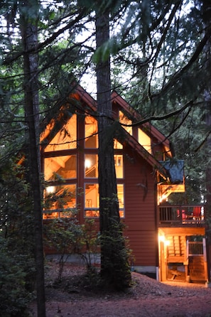 A cabin with large windows, a balcony, and a wooden deck. - Romantic island retreat surrounded by majestic trees (Shelton)