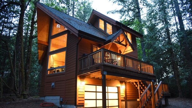 A cabin with a balcony, large windows, and a staircase leading to the entrance. - Romantic island retreat  surrounded by majestic trees (Shelton)