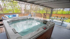 A hot tub with a control panel, a wooden deck, and a picnic table.