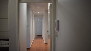 A hallway with a tiled floor, white walls, and a door with a phone on the wall. - monavale hills getaway (Harare Central)