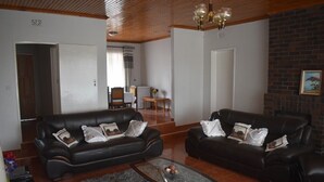 A living room with two black leather sofas, a glass coffee table, and a fireplace. - monavale hills getaway (Harare Central)