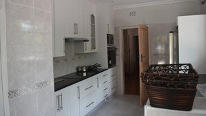 A kitchen with white cabinets, a black countertop, and a microwave. - monavale hills getaway (Harare Central)